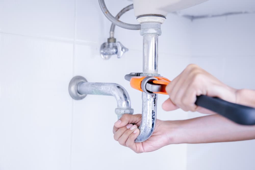 Hands of a local plumber performing essential water heater repair or faucet installation, used to advertise services in Parker, CO.